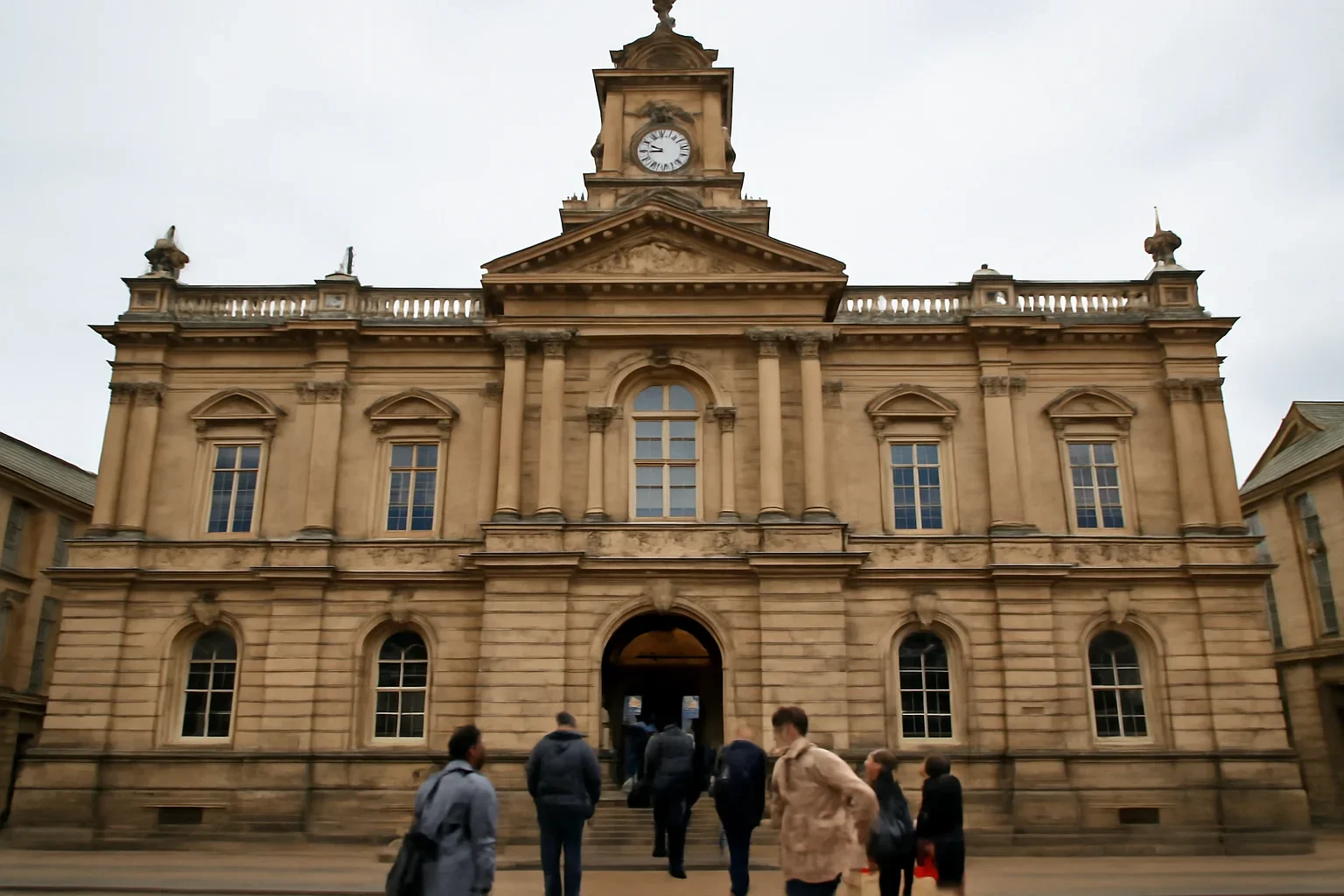 Historic UK town hall building with people entering for a council meeting